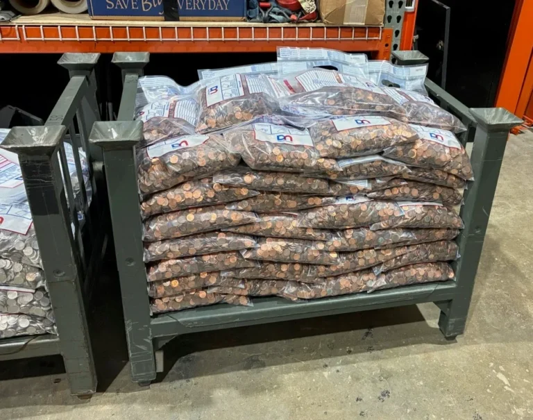 Sealed, tamper-proof bags of bulk pennies stacked on a steel rack